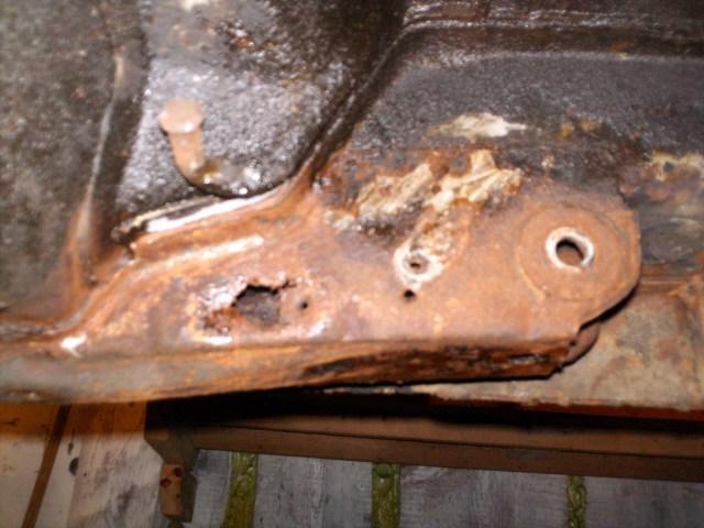Högersidans fäste sett från under bilen efter demontering av stag, handbromswire, avgasrör. Dåligt på insidan.